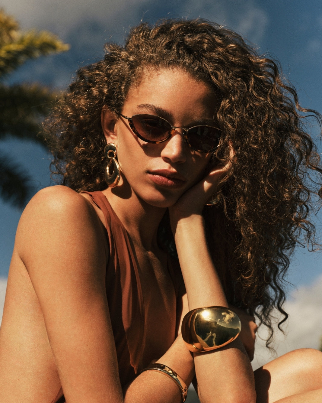a woman wearing sunglasses and a brown top