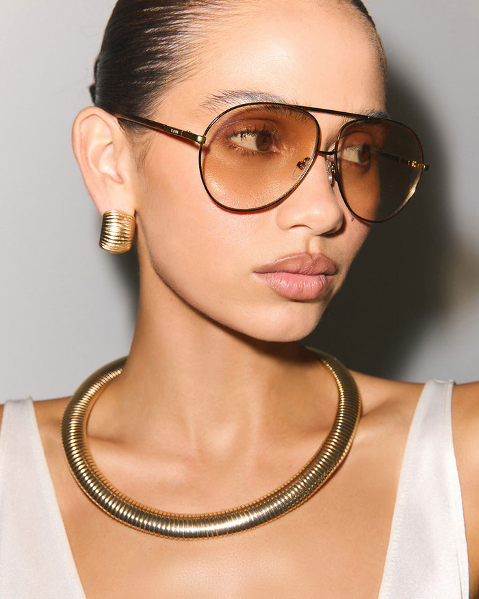 a woman wearing sunglasses and a gold necklace
