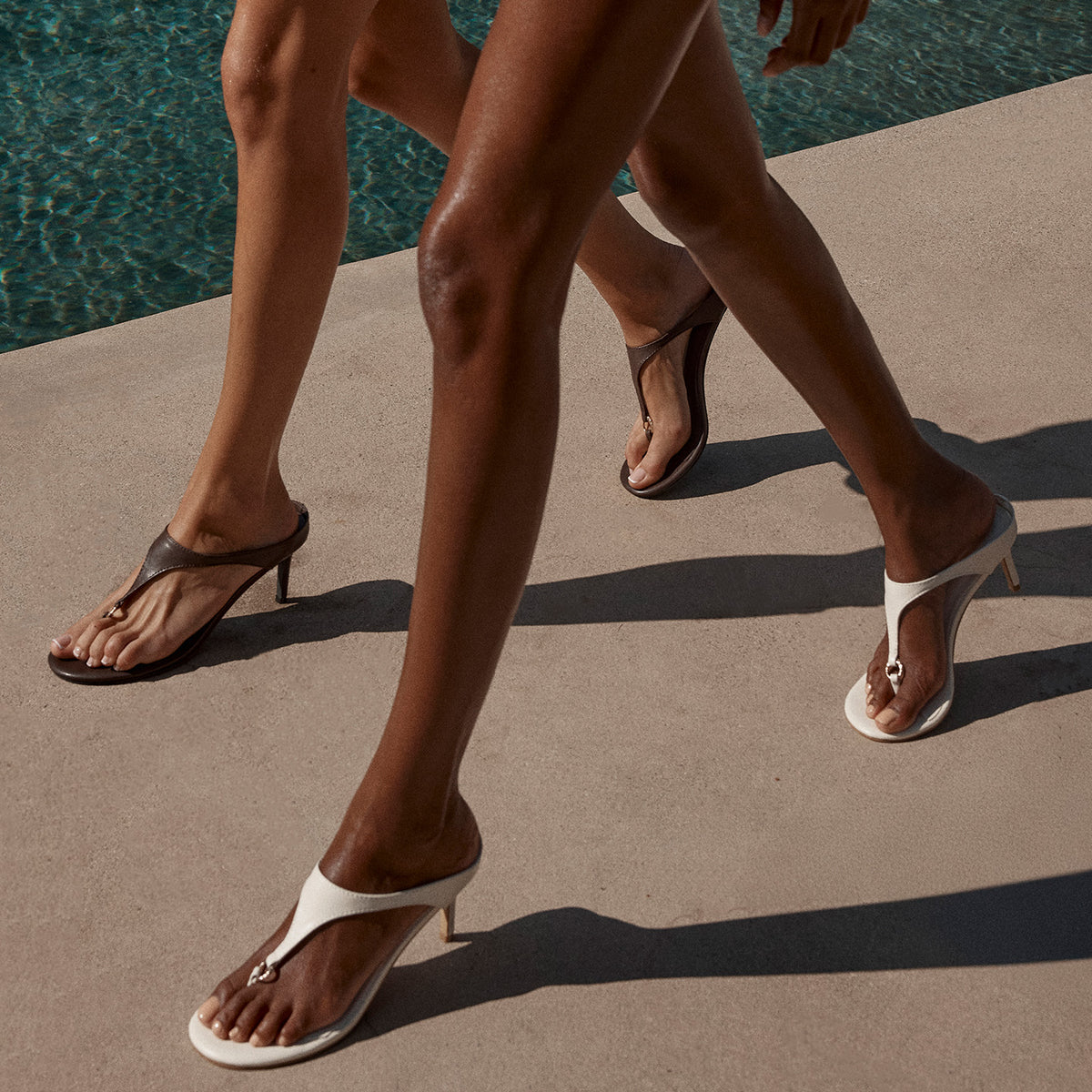 a pair of legs walking by a pool