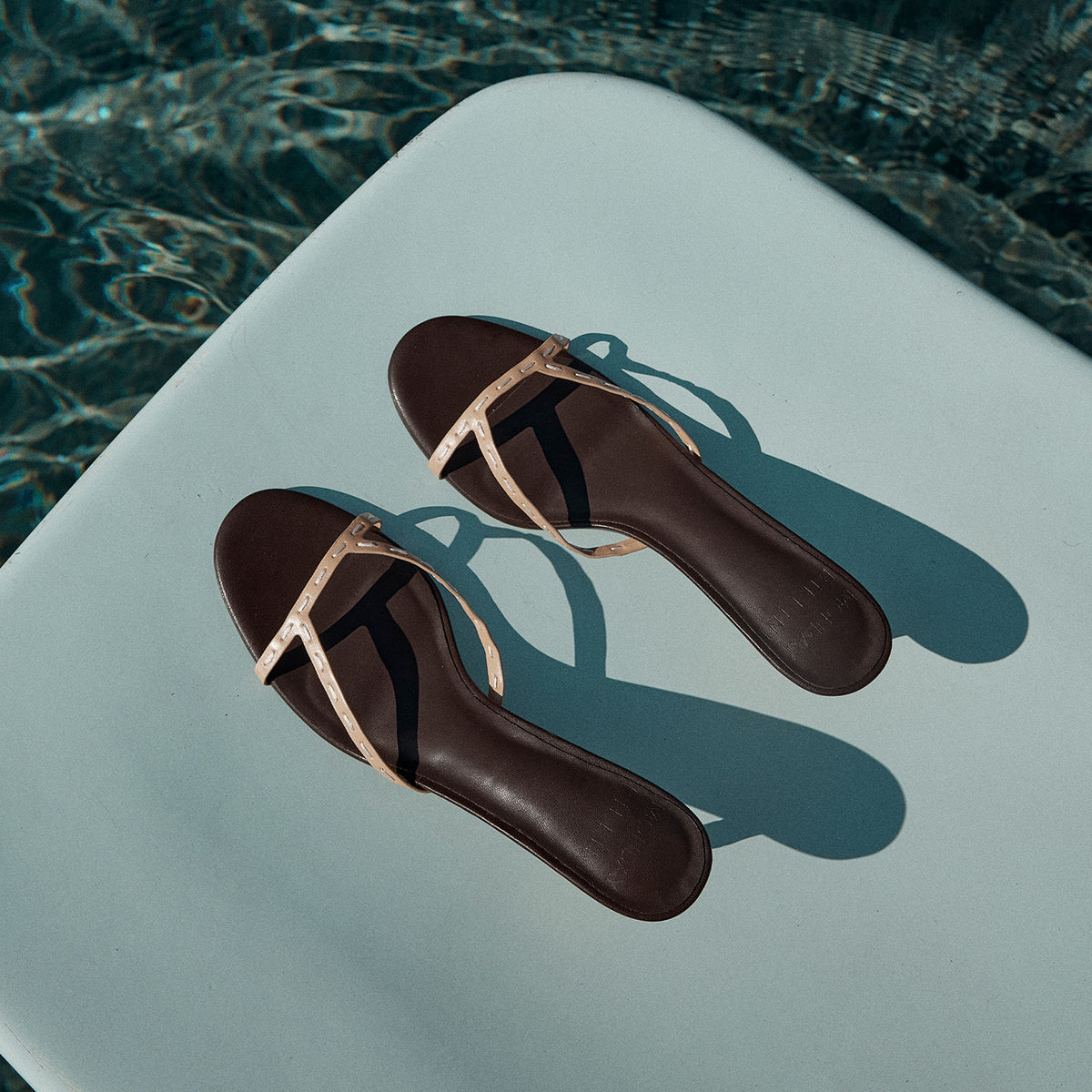 a pair of sandals on a white surface in water