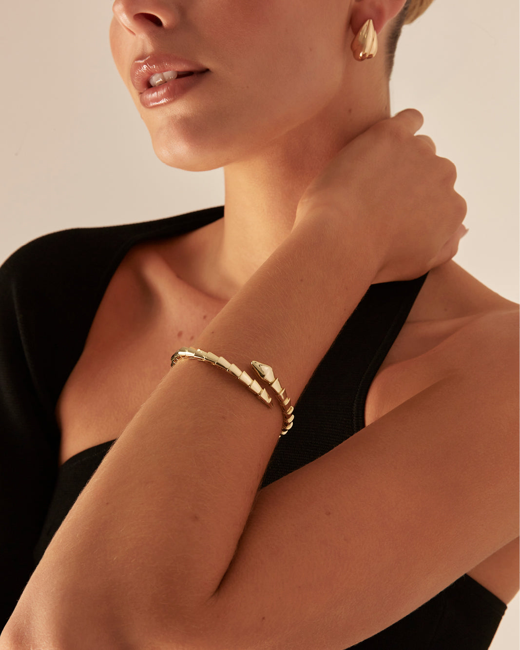 a woman wearing a gold bracelet and black top